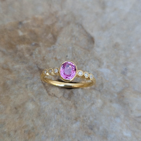 Bague en or jaune 18k sertie clos d'un saphir rose et de diamants, serti perlé