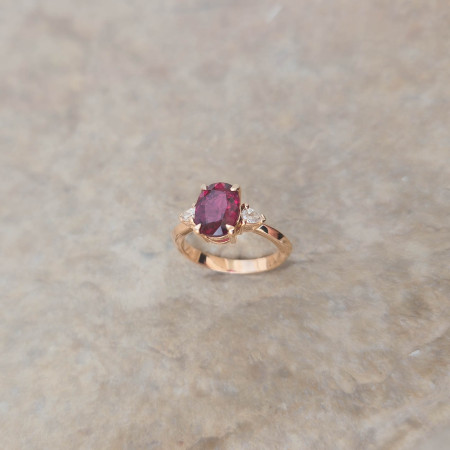Une bague en or rose 18k sertie d'une rubellite accompagnée de 2 diamants poire