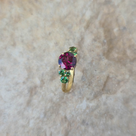 Une begue en or jaune 18k sertie au centre d'une rhodolite et de tsavorites