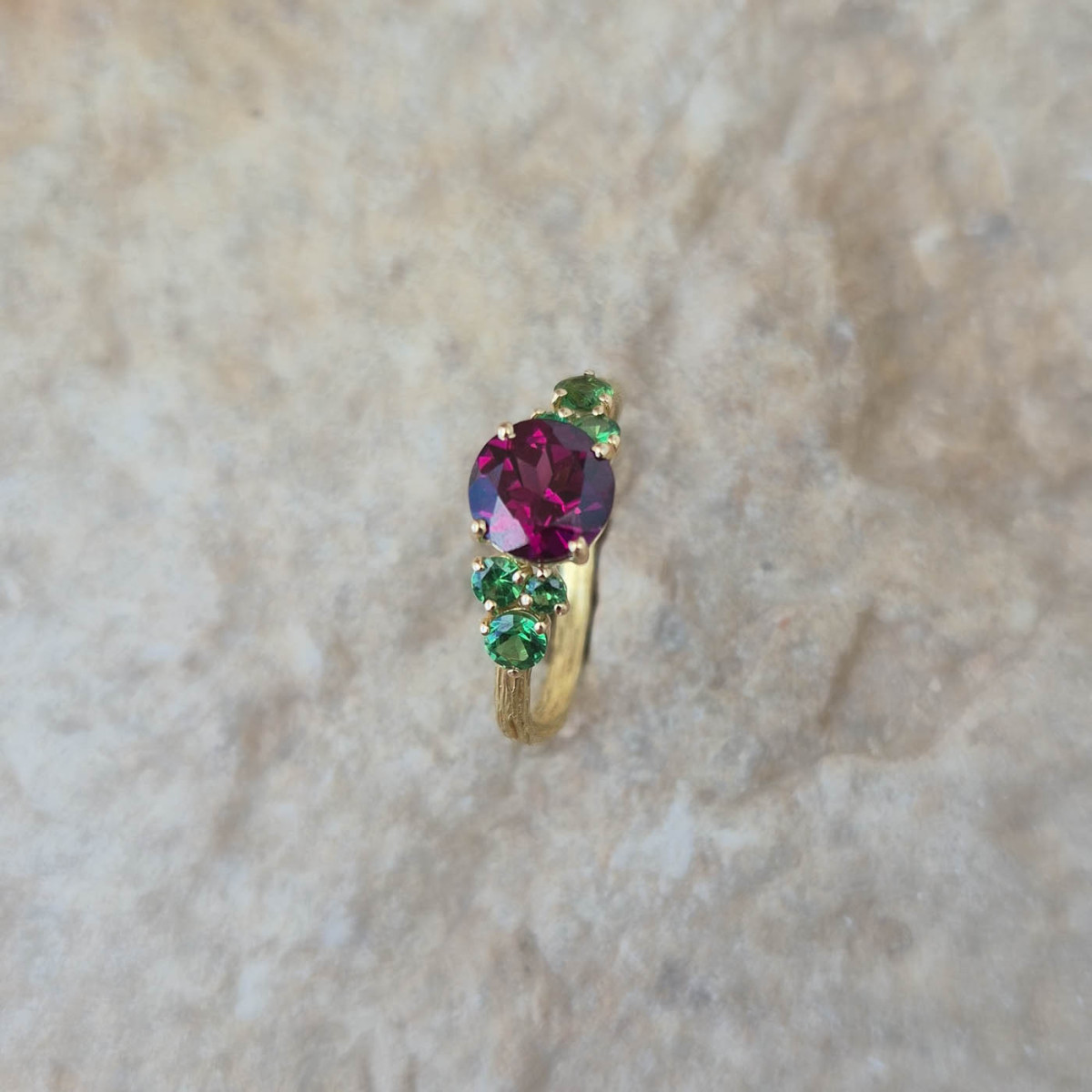 Une begue en or jaune 18k sertie au centre d'une rhodolite et de tsavorites